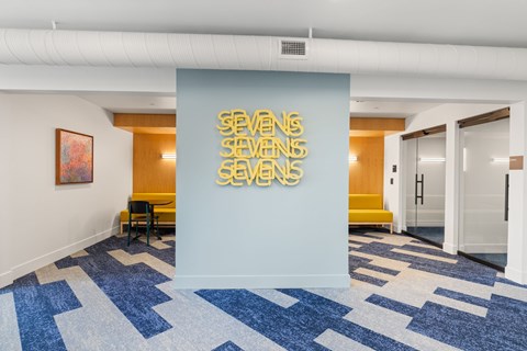 A hallway with a blue carpet and a wall with the word "SEVENS" on it.