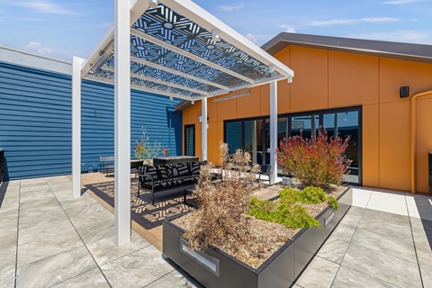 A patio with a couch and a table under a white awning.