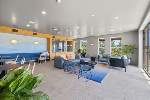 A living room with a blue rug and a large painting of the sea on the wall.