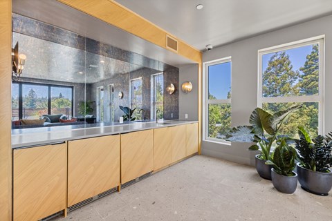 A kitchen with wooden cabinets and a large window overlooking a forest.