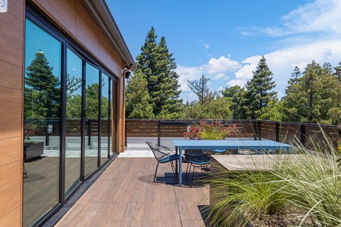 A wooden deck with a table and chairs overlooking a forest.