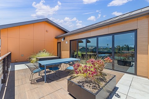 A modern house with a patio and a table set for four.