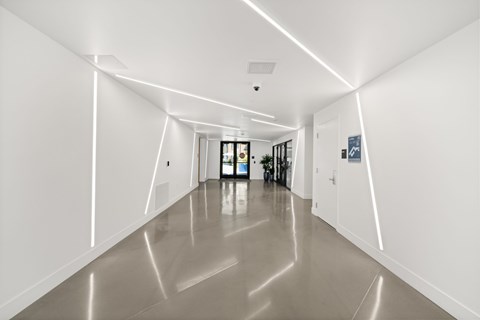 A long hallway with white walls and a reflective floor.