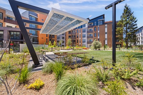 A modern outdoor seating area with a large umbrella and benches in front of a building.