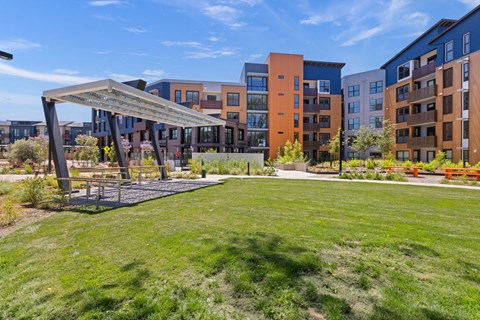 A large grassy area in front of apartment buildings with a pavilion.