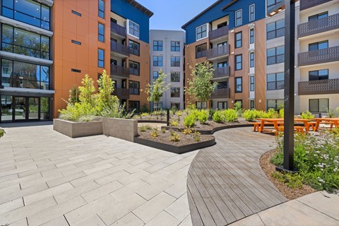 A modern courtyard with a wooden walkway and a bench.