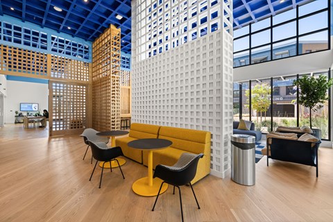 A yellow sofa and black chairs are arranged around a table in a modern room.