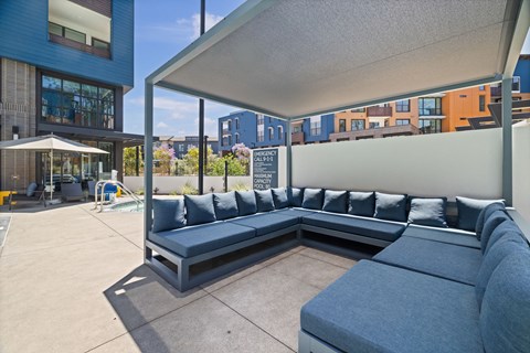 A large grey couch with pillows is in the foreground of a patio area.