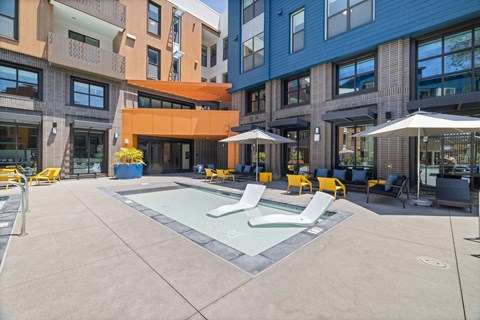 A pool area with a small pool and sun loungers.