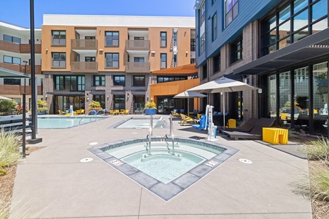 A pool area with a hot tub in the middle of a walkway.