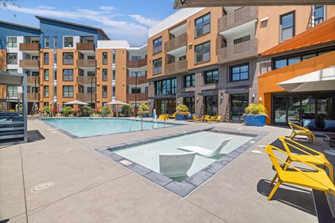 A swimming pool surrounded by yellow chairs and buildings.