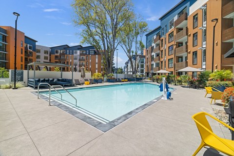 A swimming pool surrounded by yellow chairs and buildings.