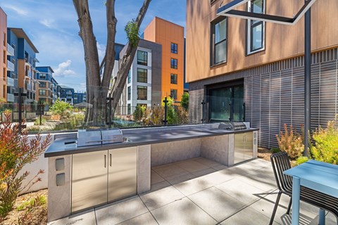A modern outdoor kitchen area with a barbecue grill and a chair.