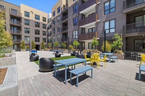 A courtyard with tables and chairs surrounded by buildings.