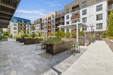 A patio area with a white umbrella and a few chairs.