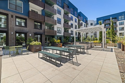 A patio with a table and chairs is surrounded by apartment buildings.
