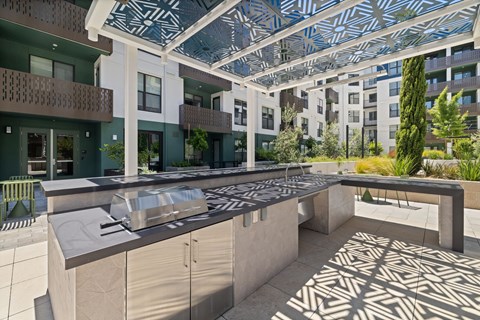 A modern outdoor kitchen area with a patterned floor and a glass roof.