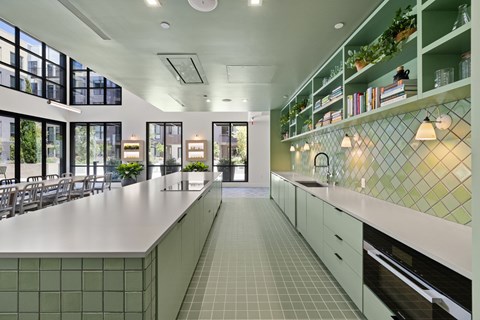 A kitchen with green tiled backsplash and white countertops.