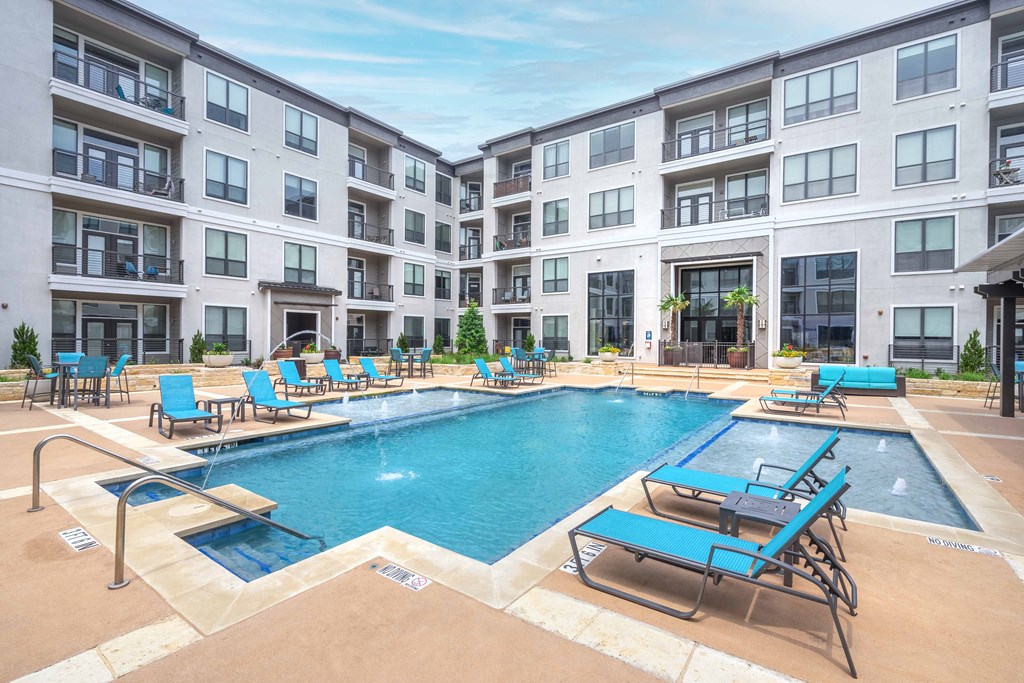 an apartment complex with a swimming pool and chaise lounge chairs