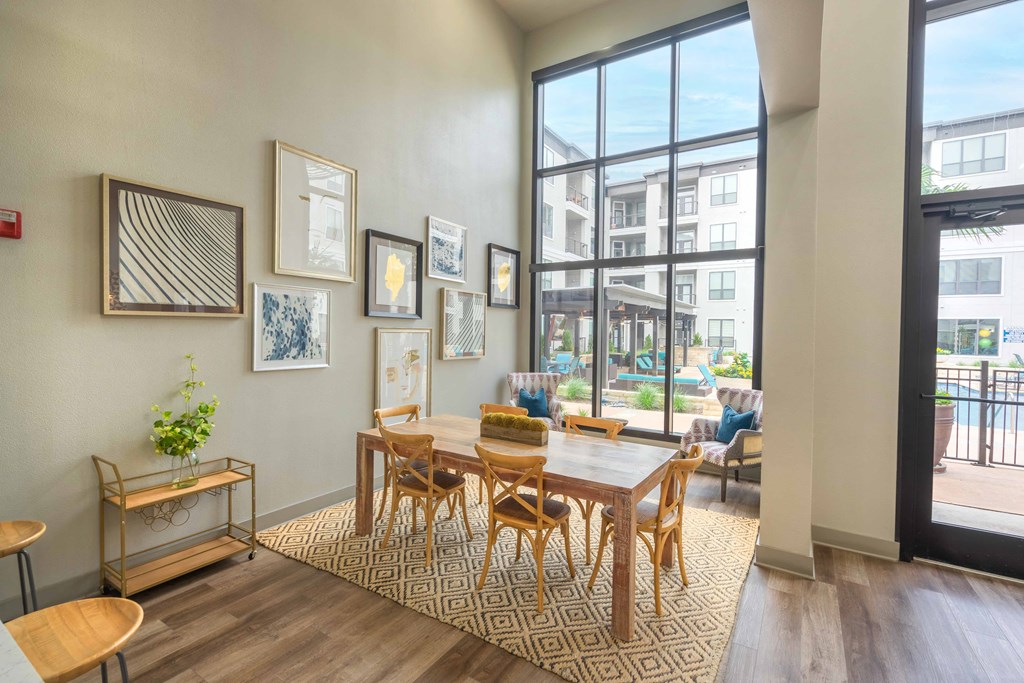 a dining area with a wooden table and chairs and a large window with a view of a pool