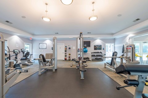 A spacious gym with various exercise equipment and a large mirror on the wall.