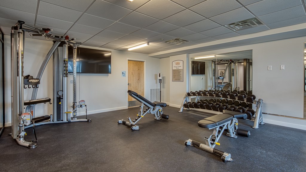 A gym with a variety of equipment including weights and a bench press.