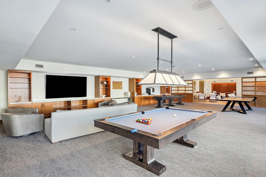 A pool table in the middle of a room with a TV and a couch.