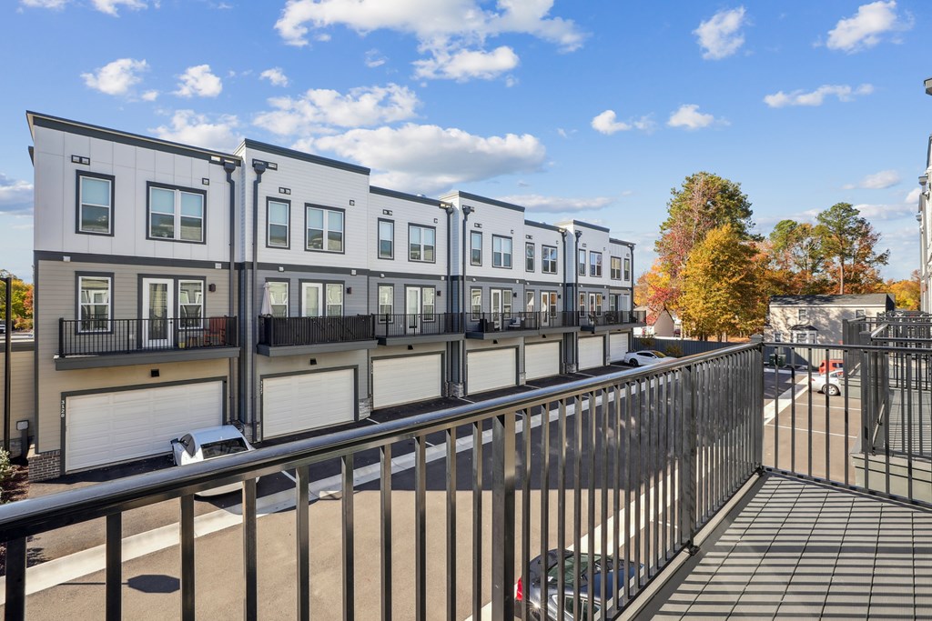A row of modern townhouses with a metal fence in front.