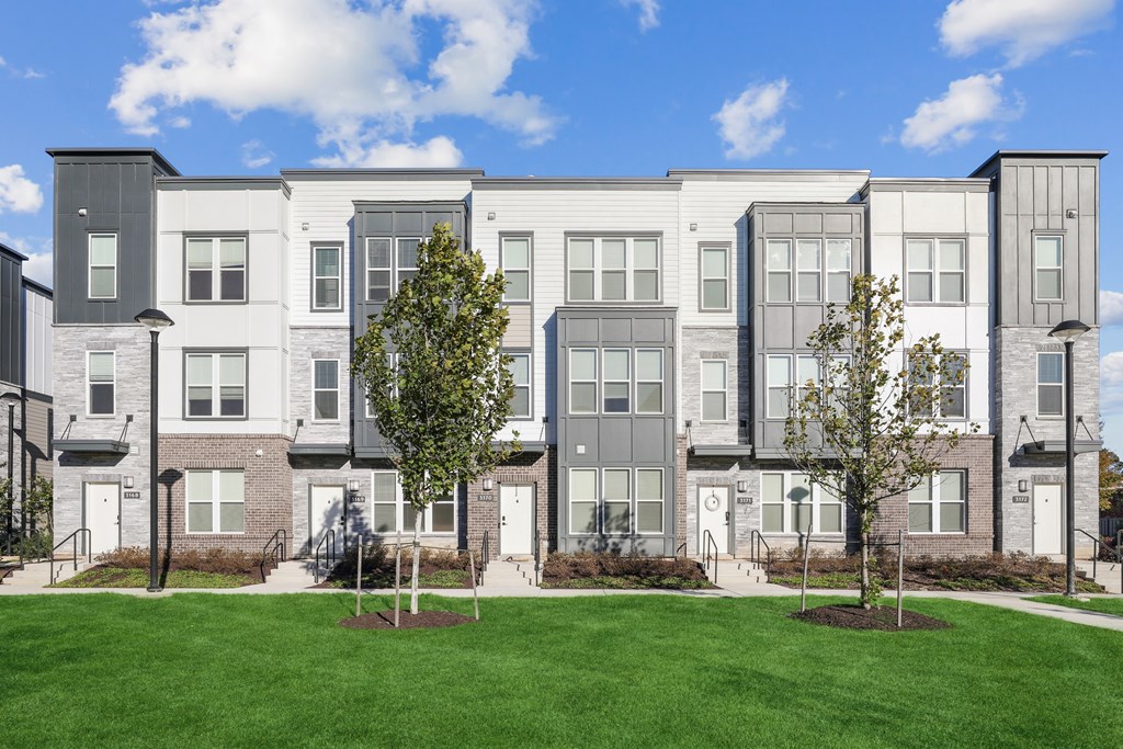 A row of modern townhouses with green lawns in front.