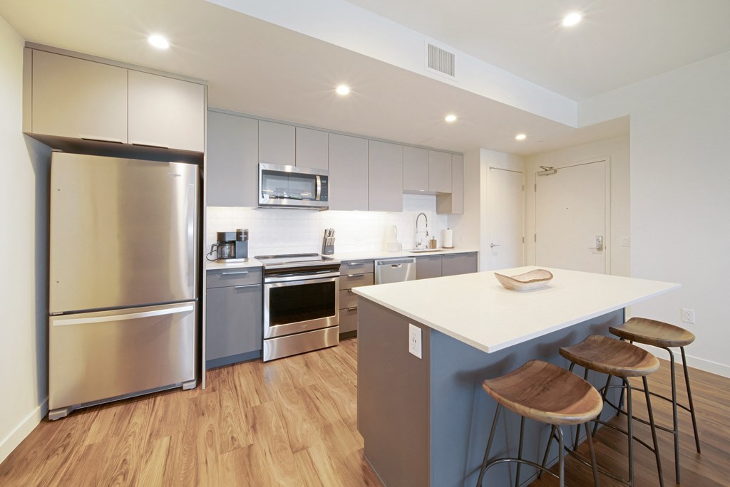 a kitchen with stainless steel appliances and a large island with three stools