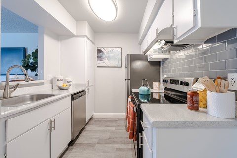 A modern kitchen with white cabinets and a grey countertop.