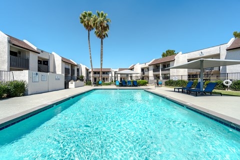 A long rectangular swimming pool in front of apartment buildings.