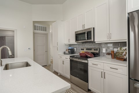 A kitchen with white cabinets and a stainless steel refrigerator.