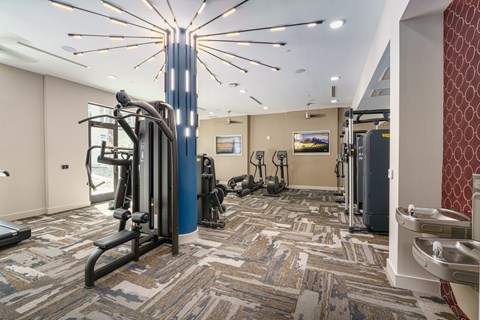 A gym with a variety of equipment including treadmills, weights, and exercise machines.