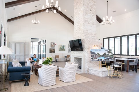 A woman is sitting on a blue couch in a spacious living room.