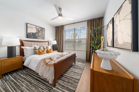 A bedroom with a bed, nightstands, and a ceiling fan.