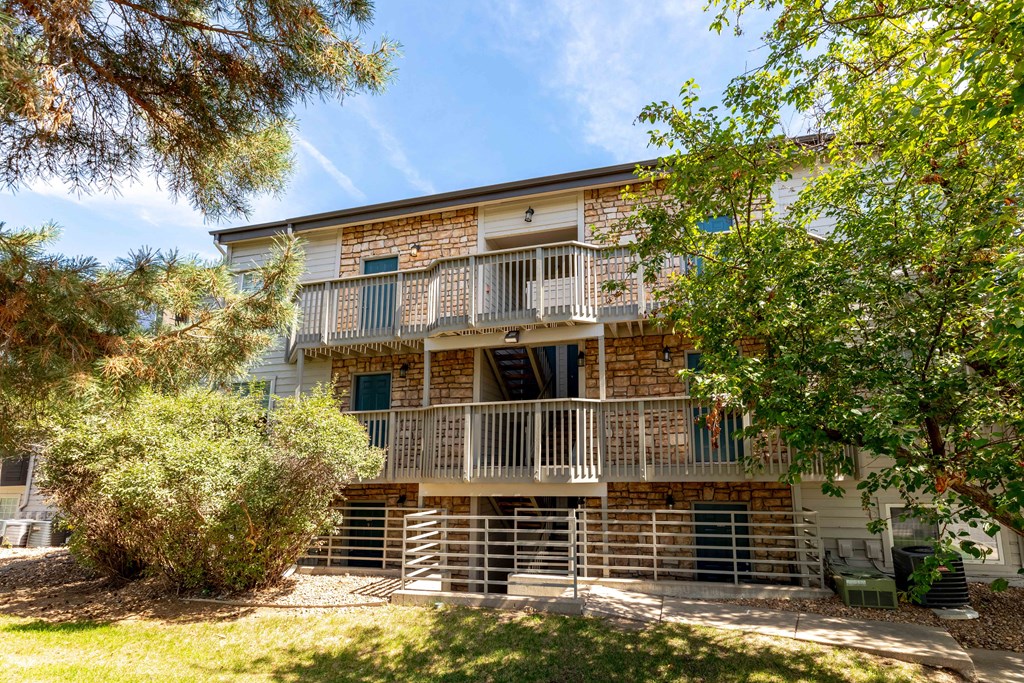 the front of a brick apartment building with a balcony and trees