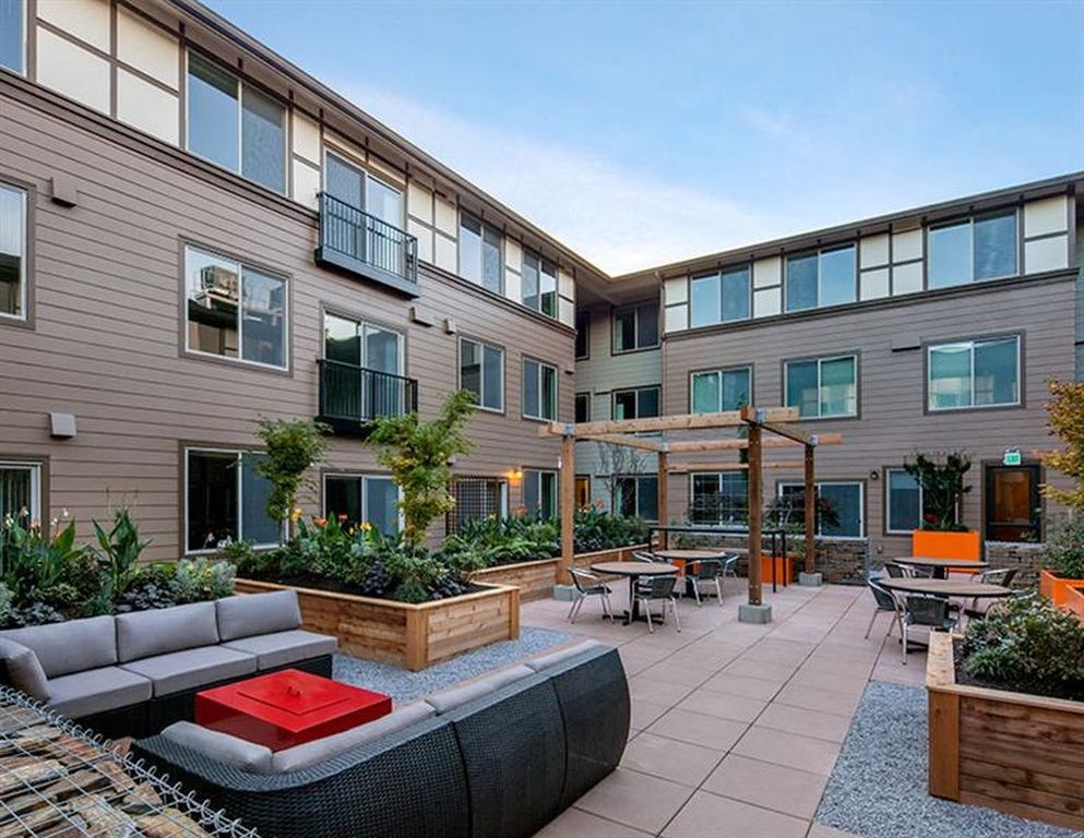 a patio with a couch and tables in front of a building