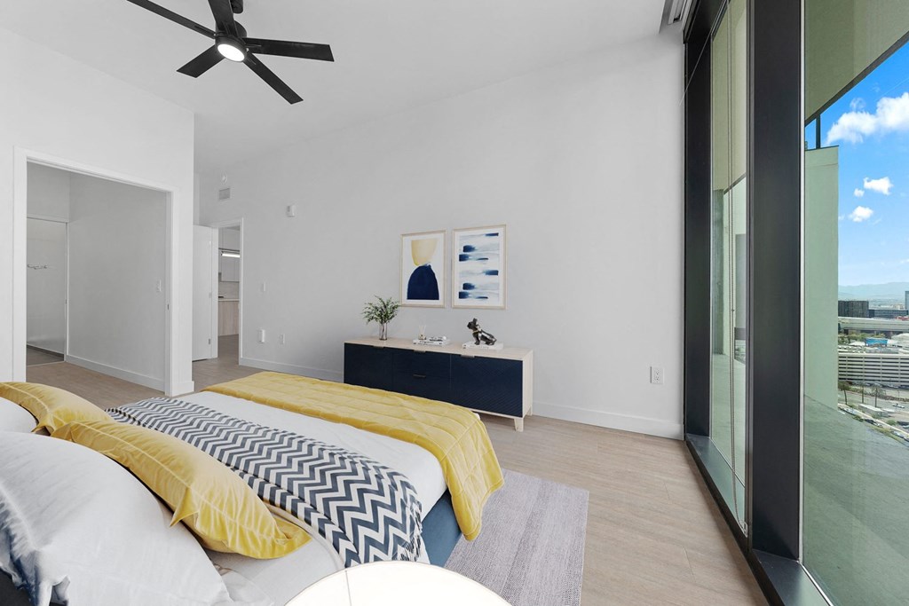 Skye on 6th bedroom with a large window, ceiling fan, wall decor