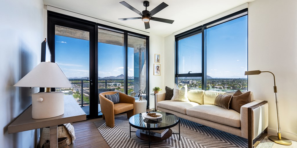 a living room with a couch and a coffee table and large windows