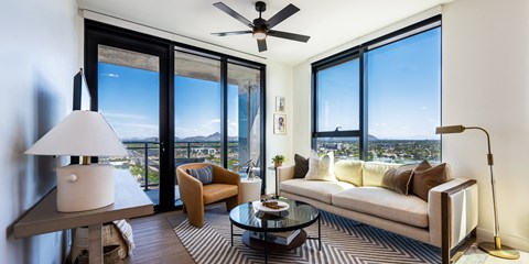 a living room with a couch and a coffee table and large windows