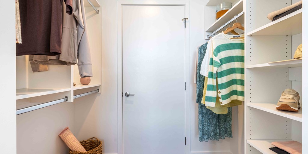 a walk in closet with white cabinets and a white door