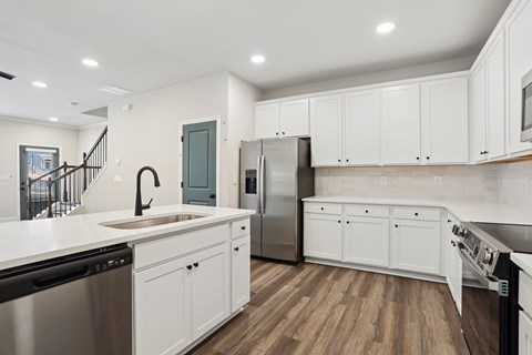 A modern kitchen with white cabinets and stainless steel appliances.