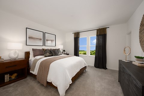 A bedroom with a large bed and a view of the outdoors through the window.