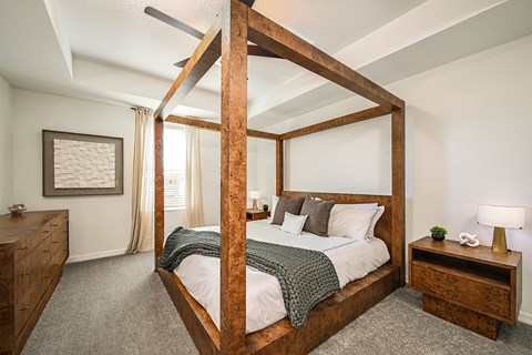 A bedroom with a four poster bed and a nightstand with a lamp.