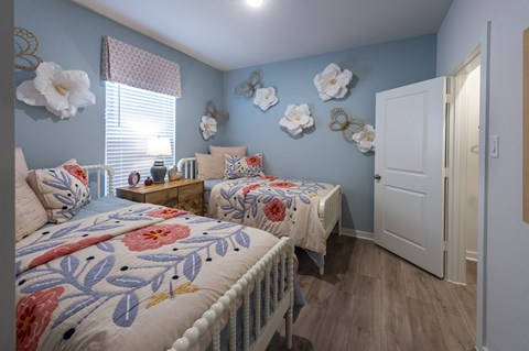 A bedroom with two beds and a white door.