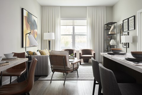 A modern dining room with a large window and a painting on the wall.