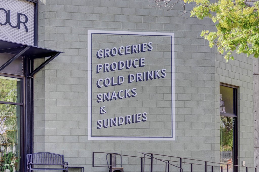 a sign on the side of a building that says groceries produce cold drinks snacks and sundries