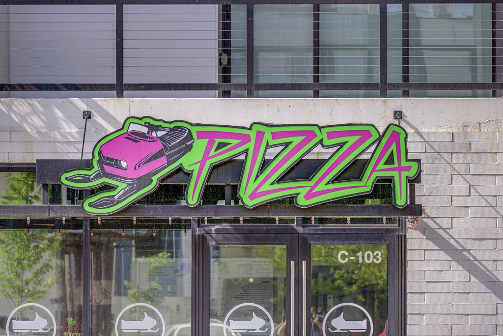 a neon sign that reads pizza on top of a building