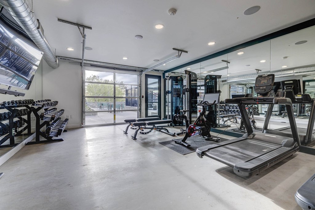 a gym with treadmills and other exercise equipment in a glass walled room